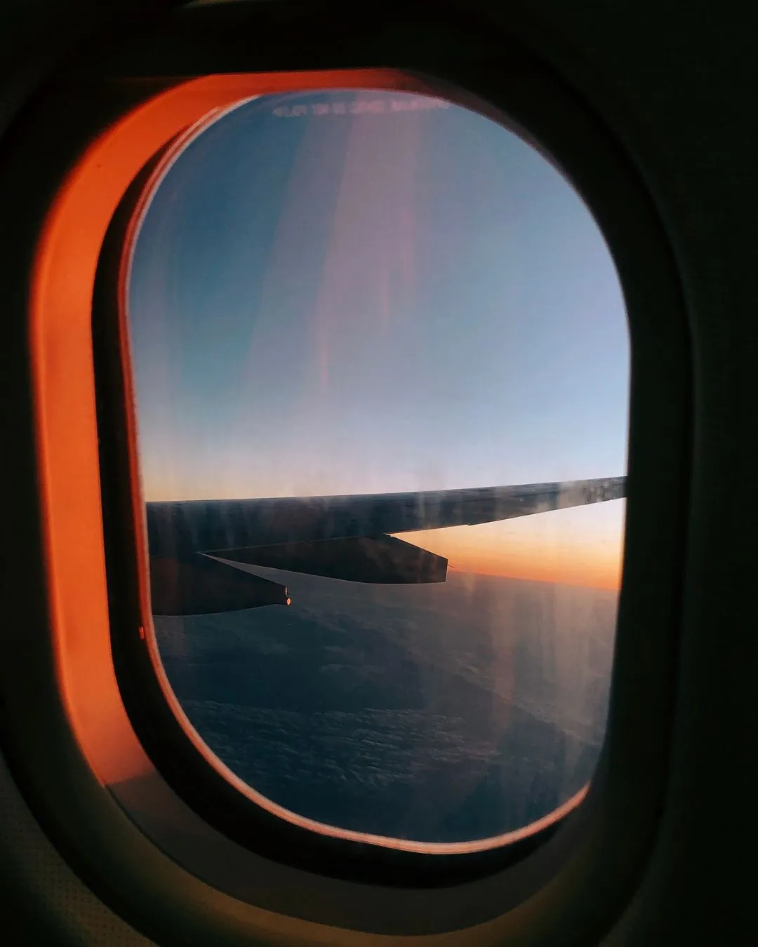 View from an aircraft window over the clouds at sunset